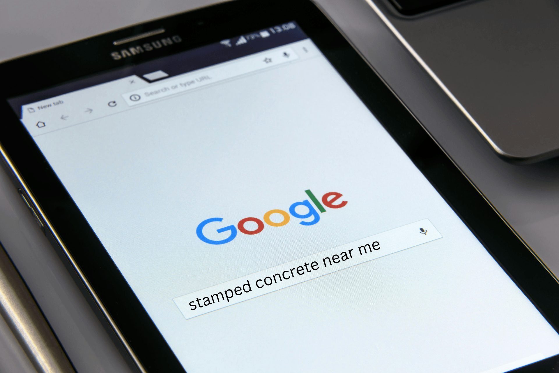 Someone searching on Google on their Samsung tablet for stamped concrete near me